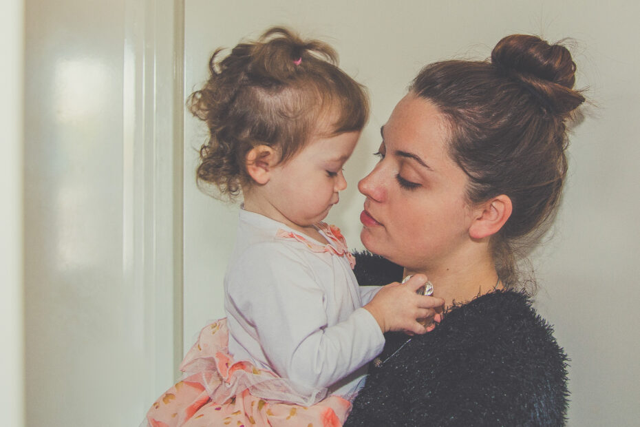 Woman in black shirt holding a little girl in a white and pink long sleeve shirt. Photo by Gabrielle Riddell on scopio.