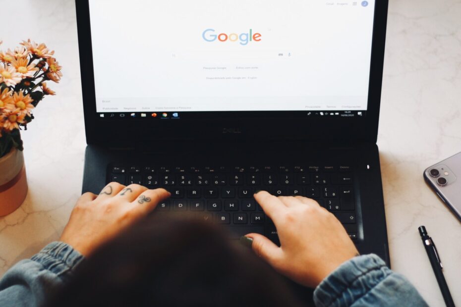 An over-the-head shot of someone using a laptop. The homepage of Google's search engine is displayed on the screen, as if the user is about to perform a search.